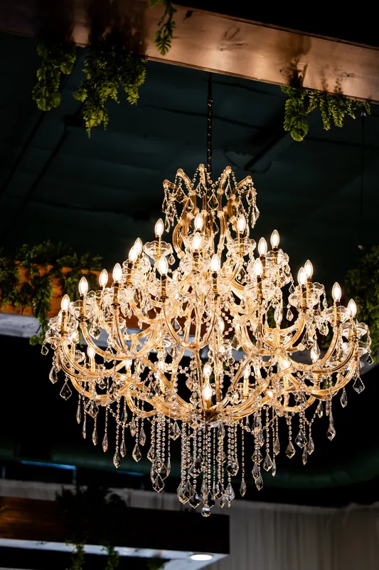 One of The Arabella\'s chandeliers above white drapery and greenery in the Halo Room