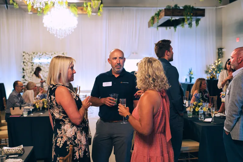 Professionals mingling with drinks in Solara Hall during a networking event