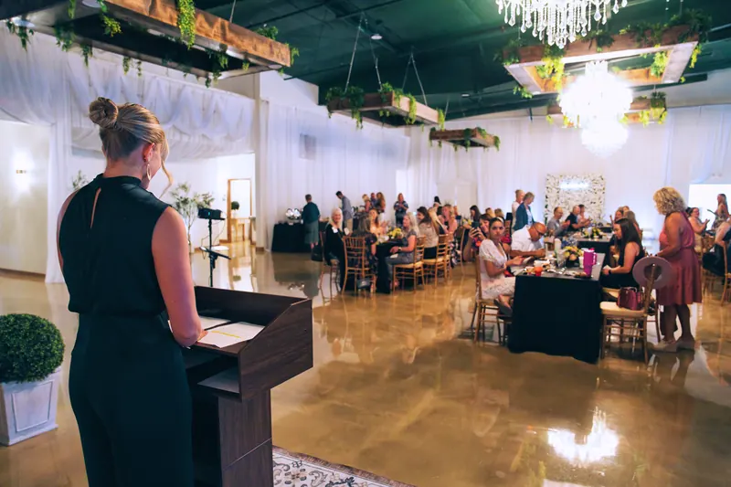 A speaker at the podium addressing a full Solara Hall during CREW Northern Colorado's 20th anniversary celebration