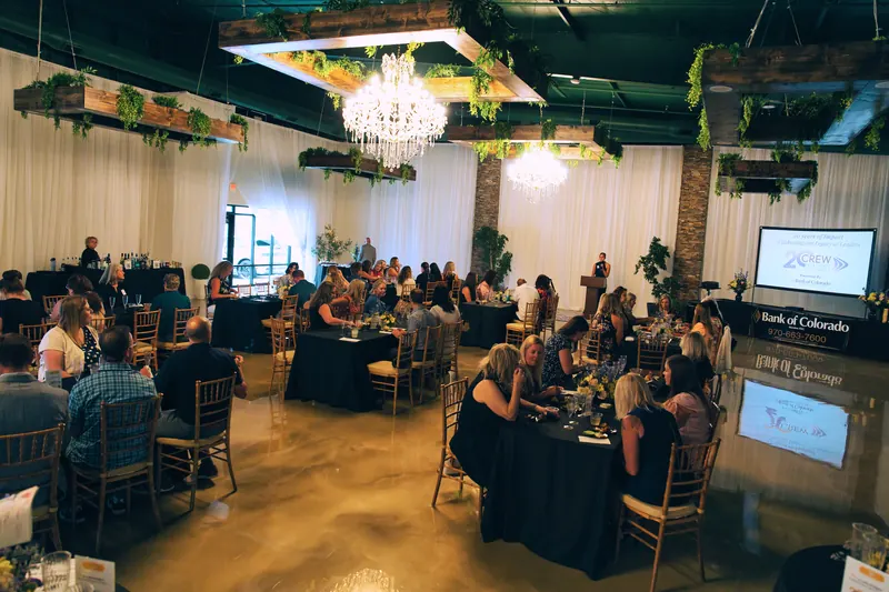 Seated rounds with black linens and a presentation screen in Solara Hall during a real corporate celebration